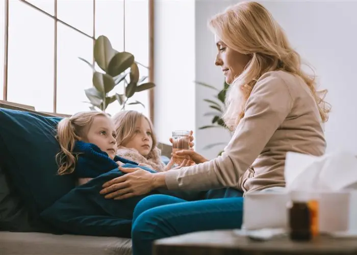 Frau kümmert sich um ihre kranken Kinder auf einer Couch