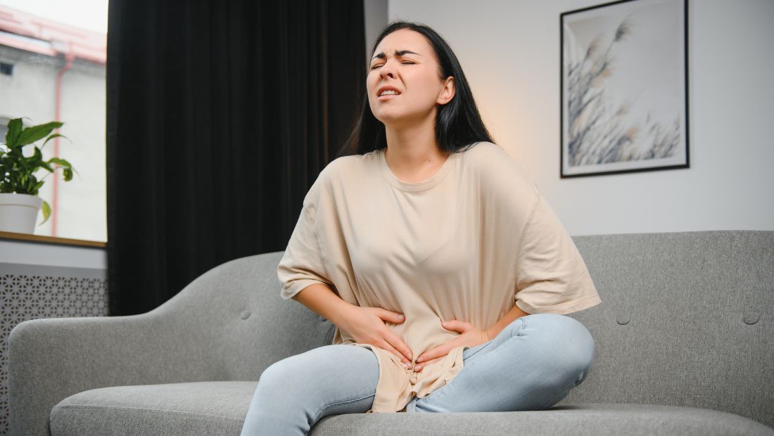 Žena si drží podbřišek, bolest při zánětu močových cest