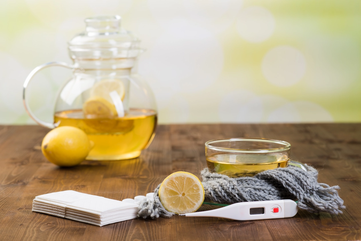 Tee, Zitrone, Taschentücher und Thermometer auf einem Tisch