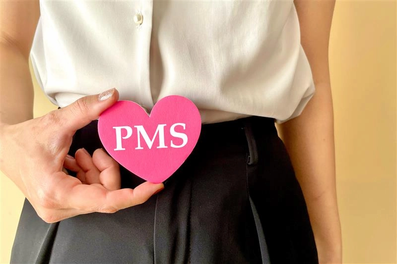 Frau hält Herz mit PMS-Aufschrift